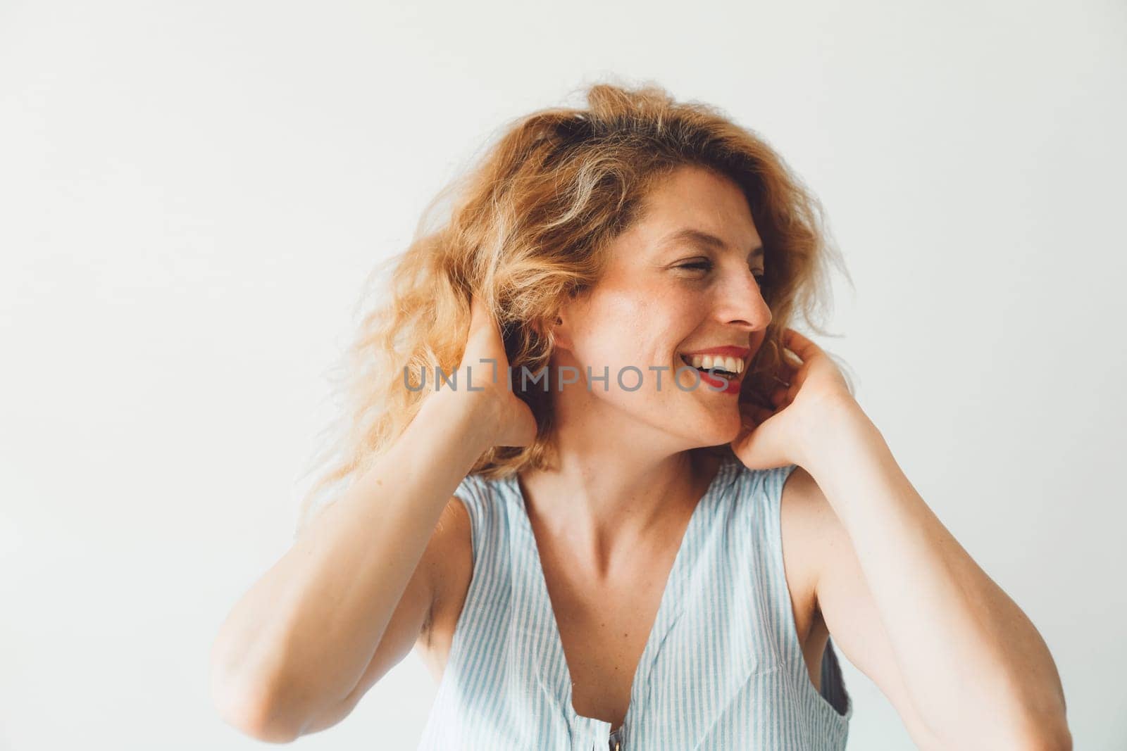 Portrait of a smiling woman playing with her hair on a white background by VisualProductions