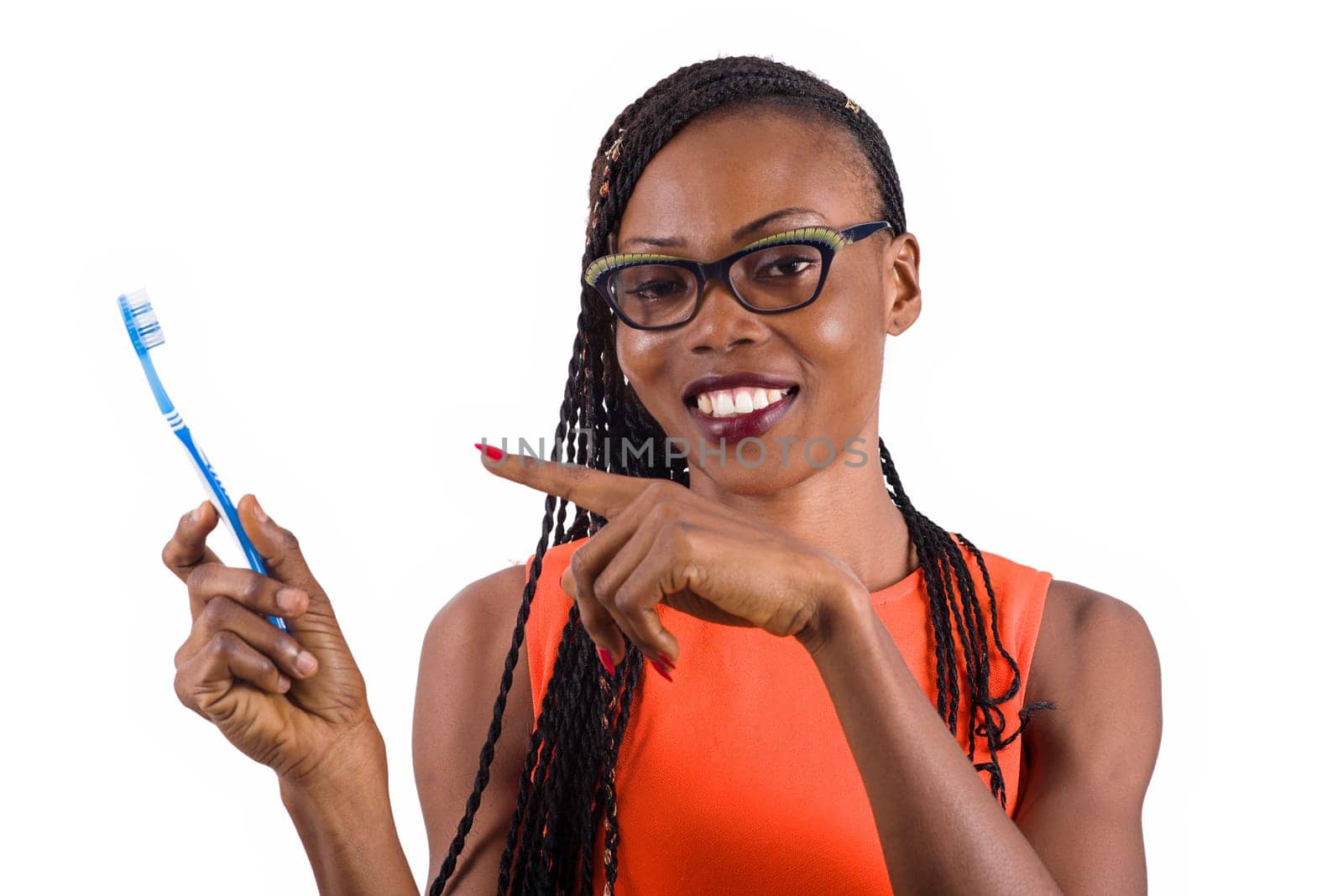 young girl standing in glasses on a white background smiling to present a toothbrush.