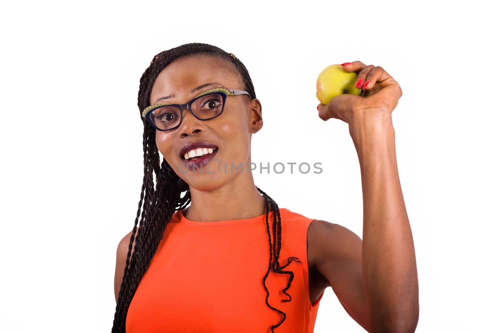 young girl standing in eyeglasses on white background smiling with an apple in her hand.