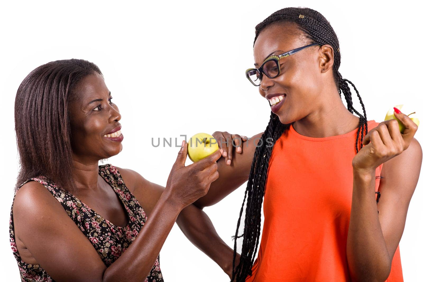 young woman standing on white background shows apple to her little sister by smiling him.