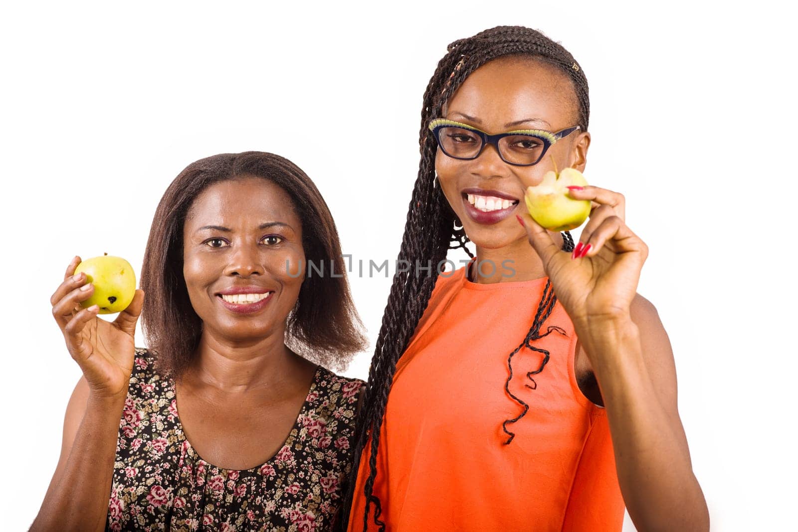 young women standing on white background showing apples while smiling on camera.
