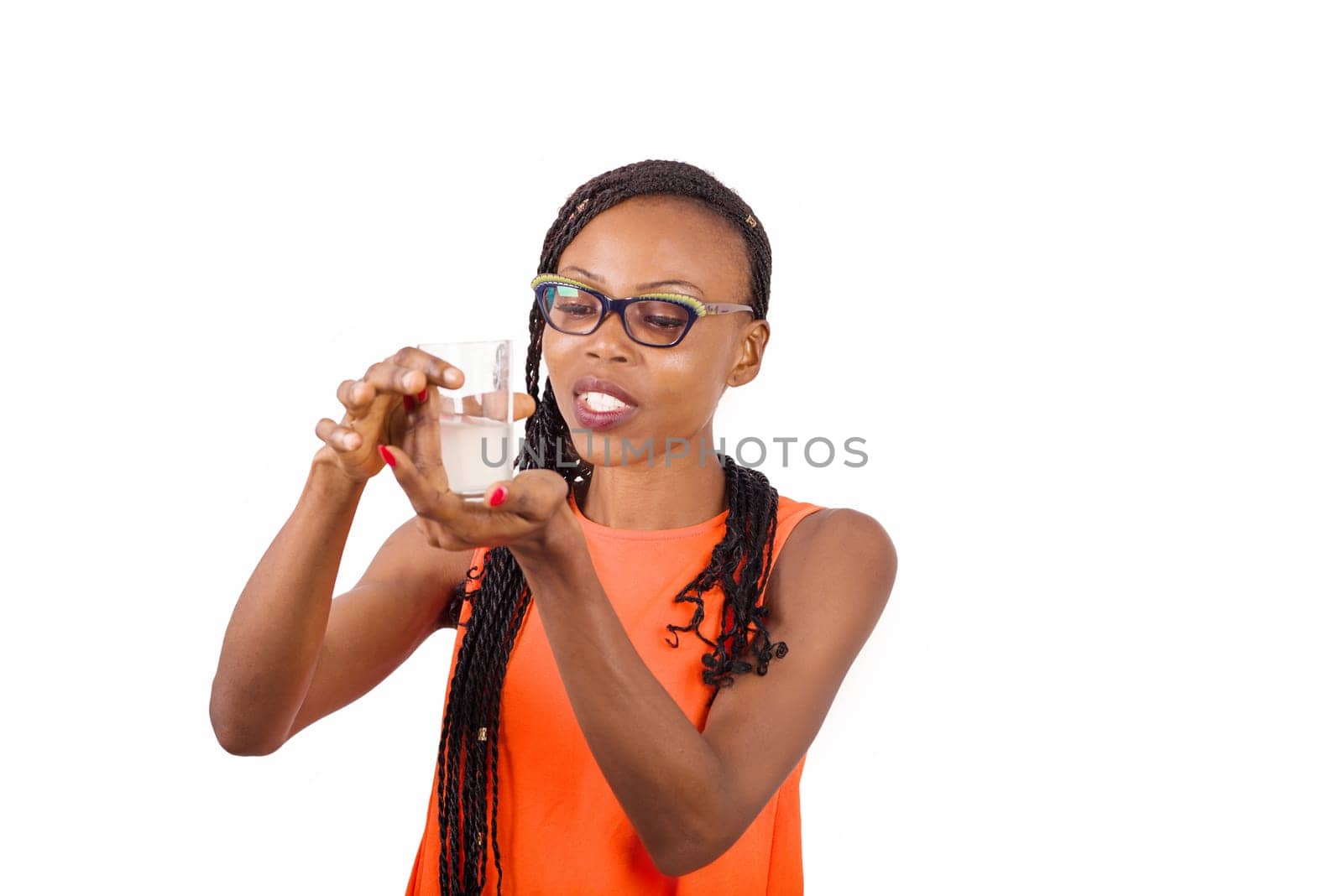 young girl standing in glasses watching a glass half full smiling.
