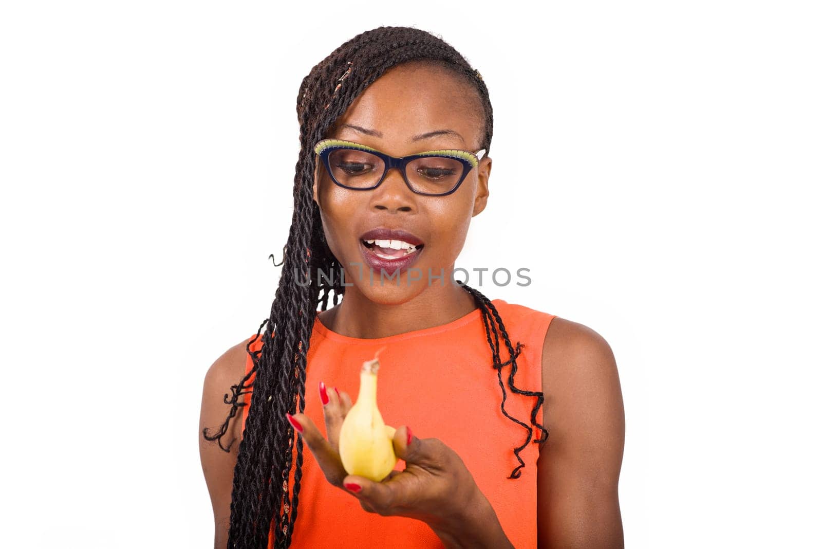 young girl standing in glasses on white background looking at a banana, surprise.