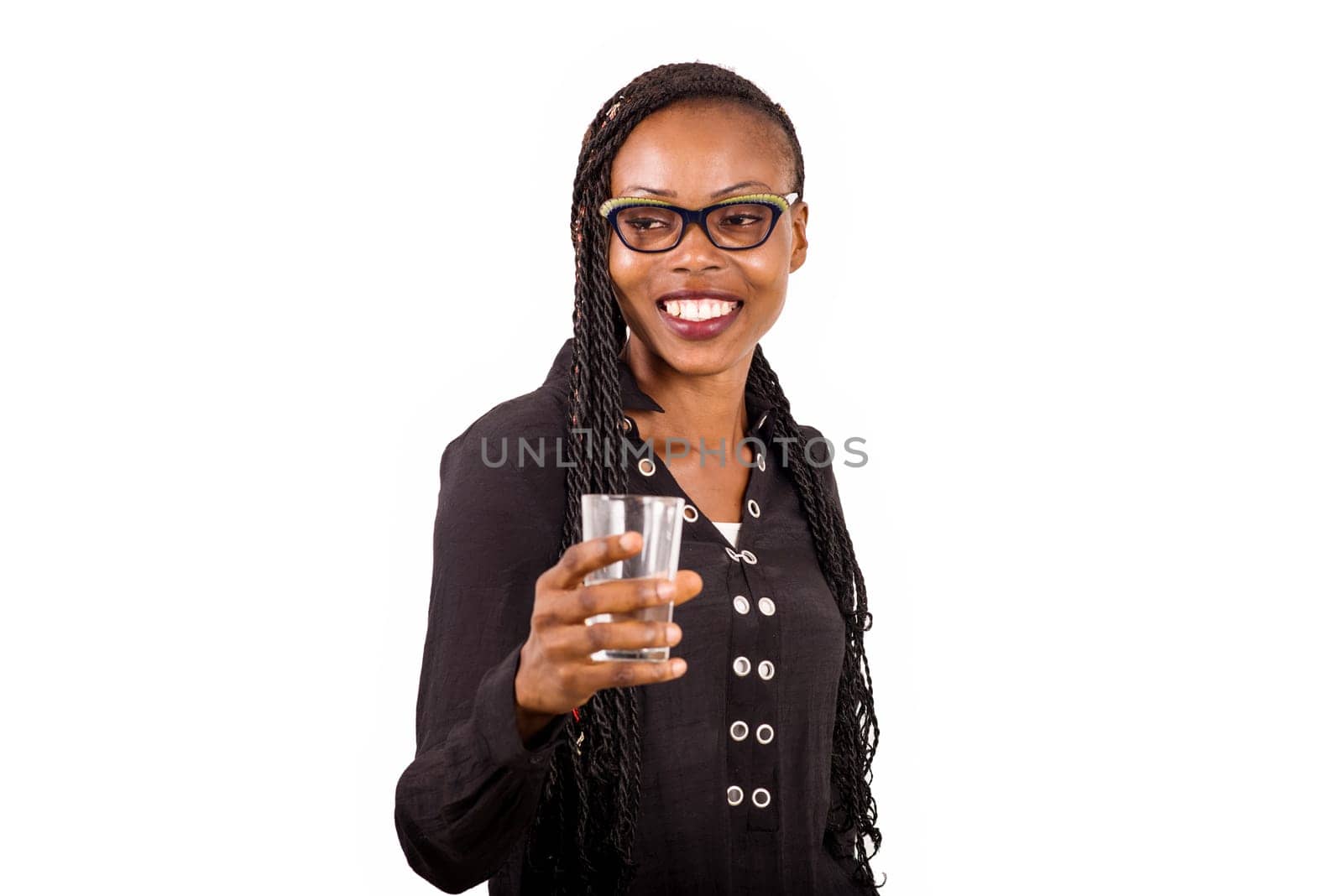 young woman standing on white background in glasses with a glass of water in hand smiling at the camera.