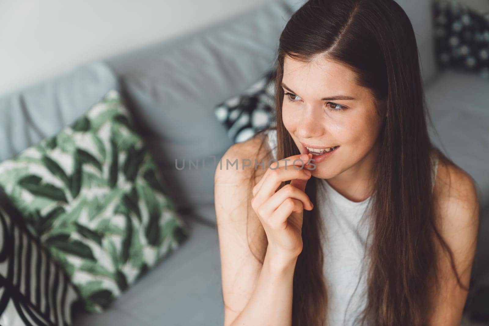 Smiling young caucasian woman taking her morning supplements, vitamin pills with a glass of water at home. High quality photo