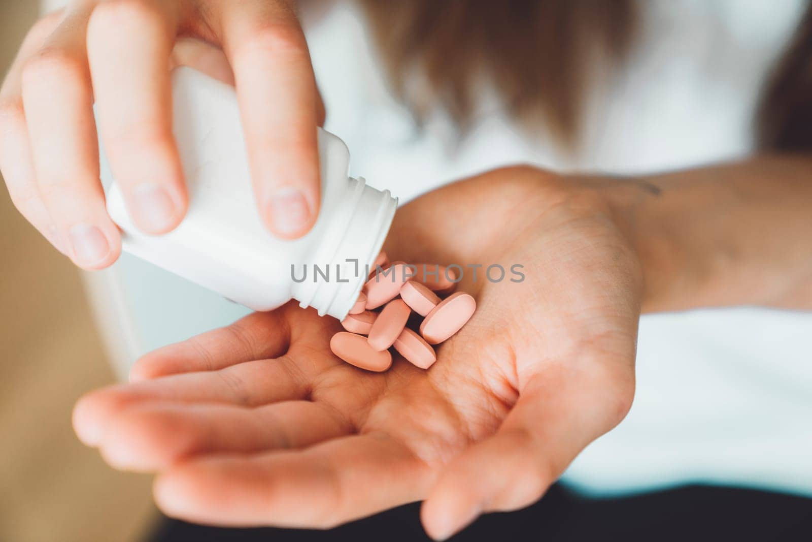 Close up woman hands holding vitamin pills, shaking them out of the bottle on the palm of her hand by VisualProductions