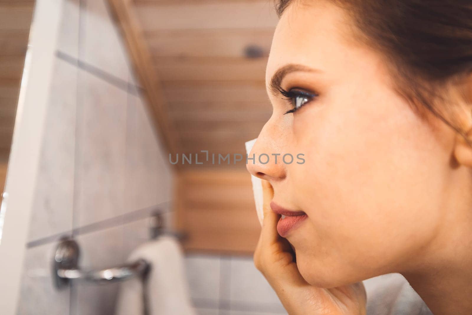 Close up side view of womans face removing make up with a cotton pad by VisualProductions