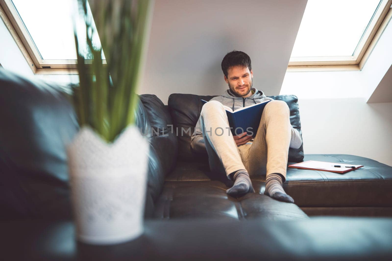 Front view of a man laying on the sofa studying from home by VisualProductions