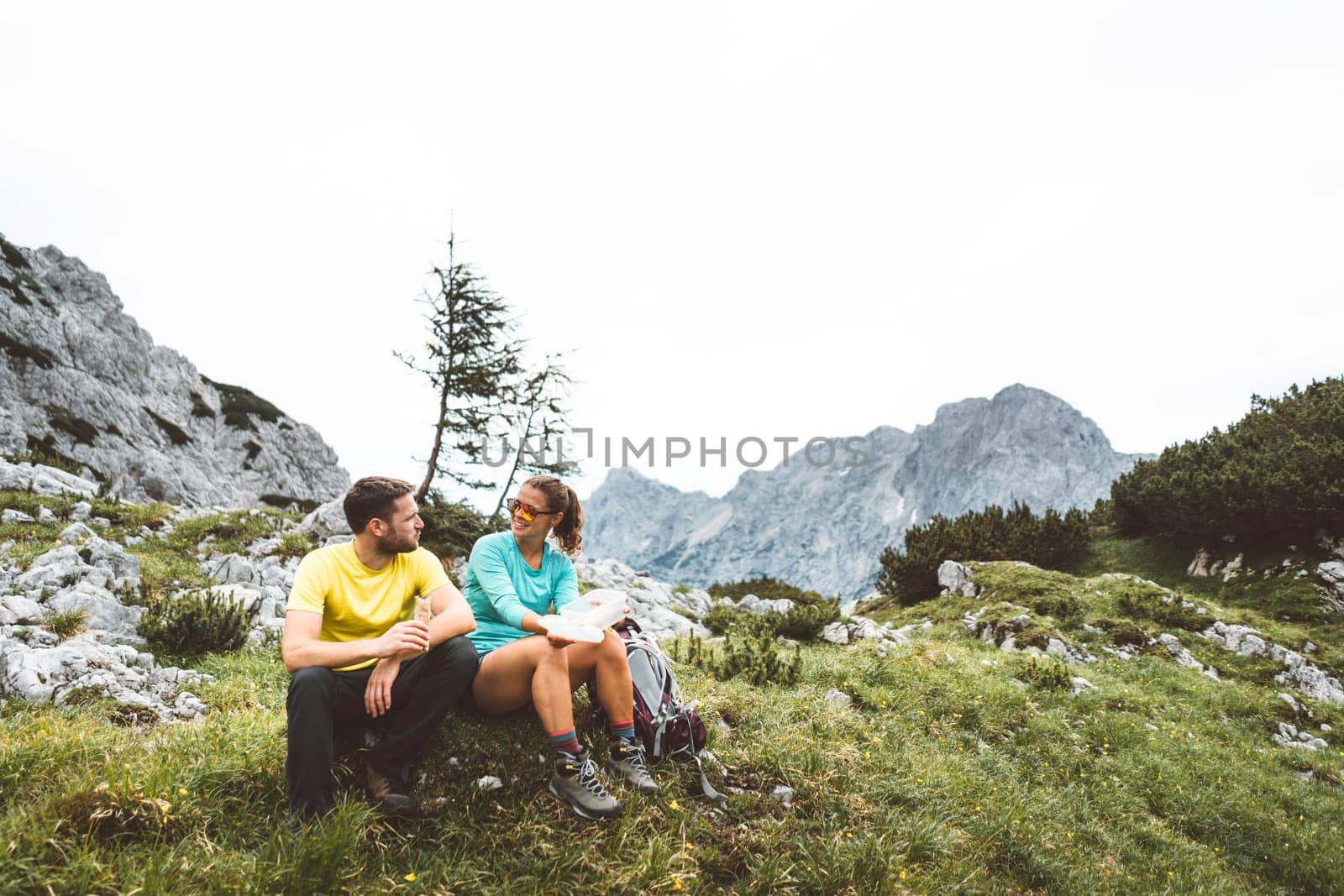 Couple of Young Happy Travelers Hiking with Backpacks on the Beautiful trail in European Alps early in the morning. Travel and Adventure Concept. High quality photo