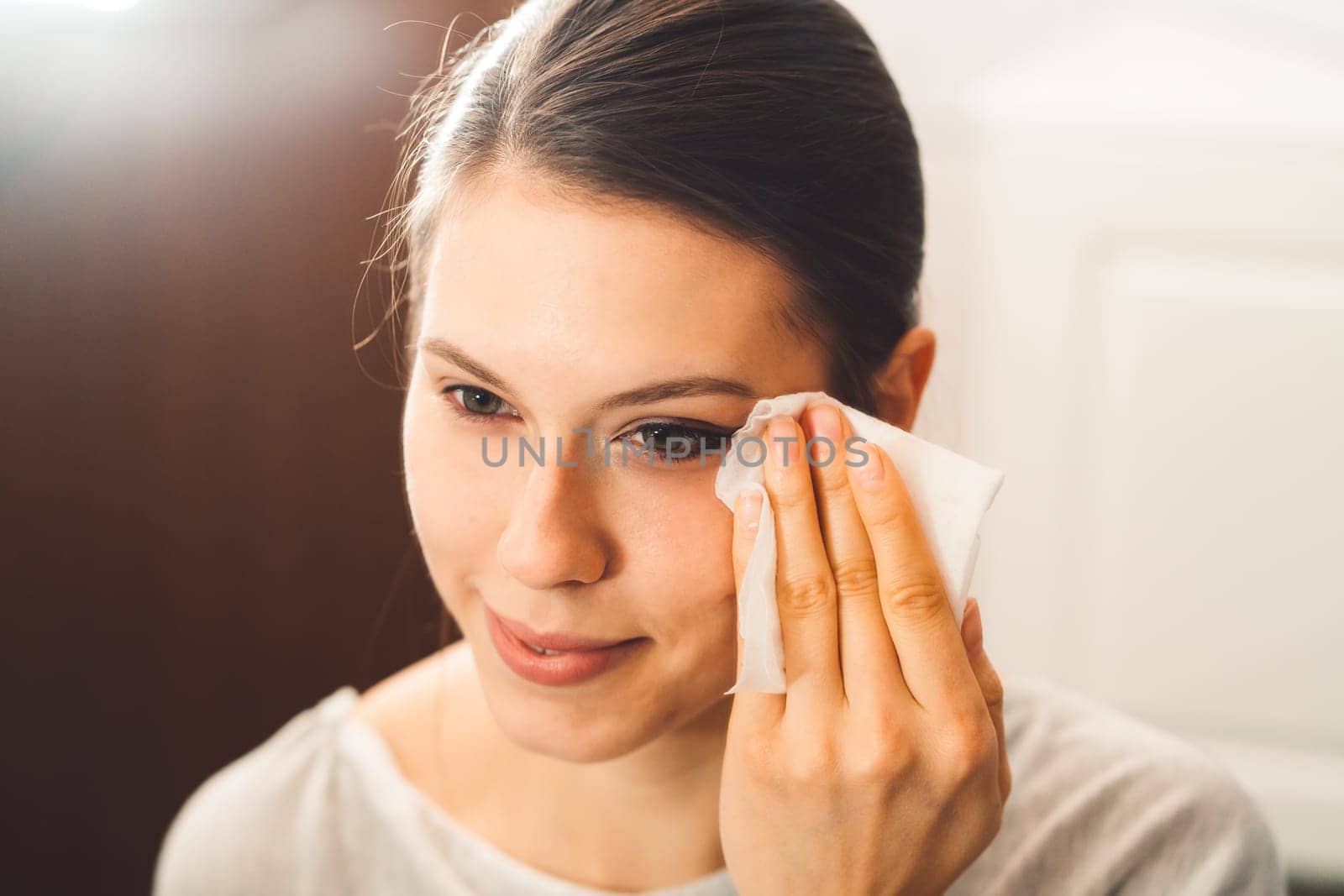 Beautiful young woman cleaning her face, removing make up with a cotton pad and micellar water. Skin care and beauty. Young beautiful woman cleaning her face. High quality photo