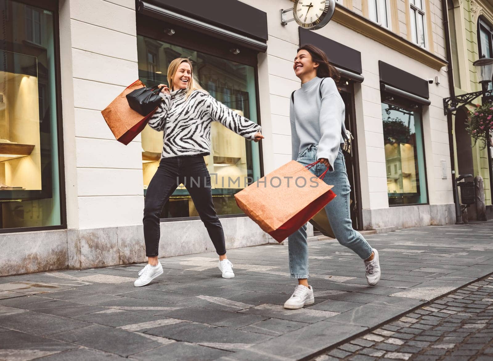 Two young caucasian women having fun on city street outdoors - Best friends enjoying a holiday day out together - Happy lifestyle, youth and young females concept. High quality photo