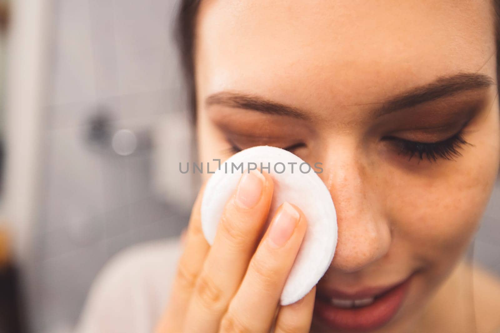 Close up woman removing eye make up with a cotton pad by VisualProductions