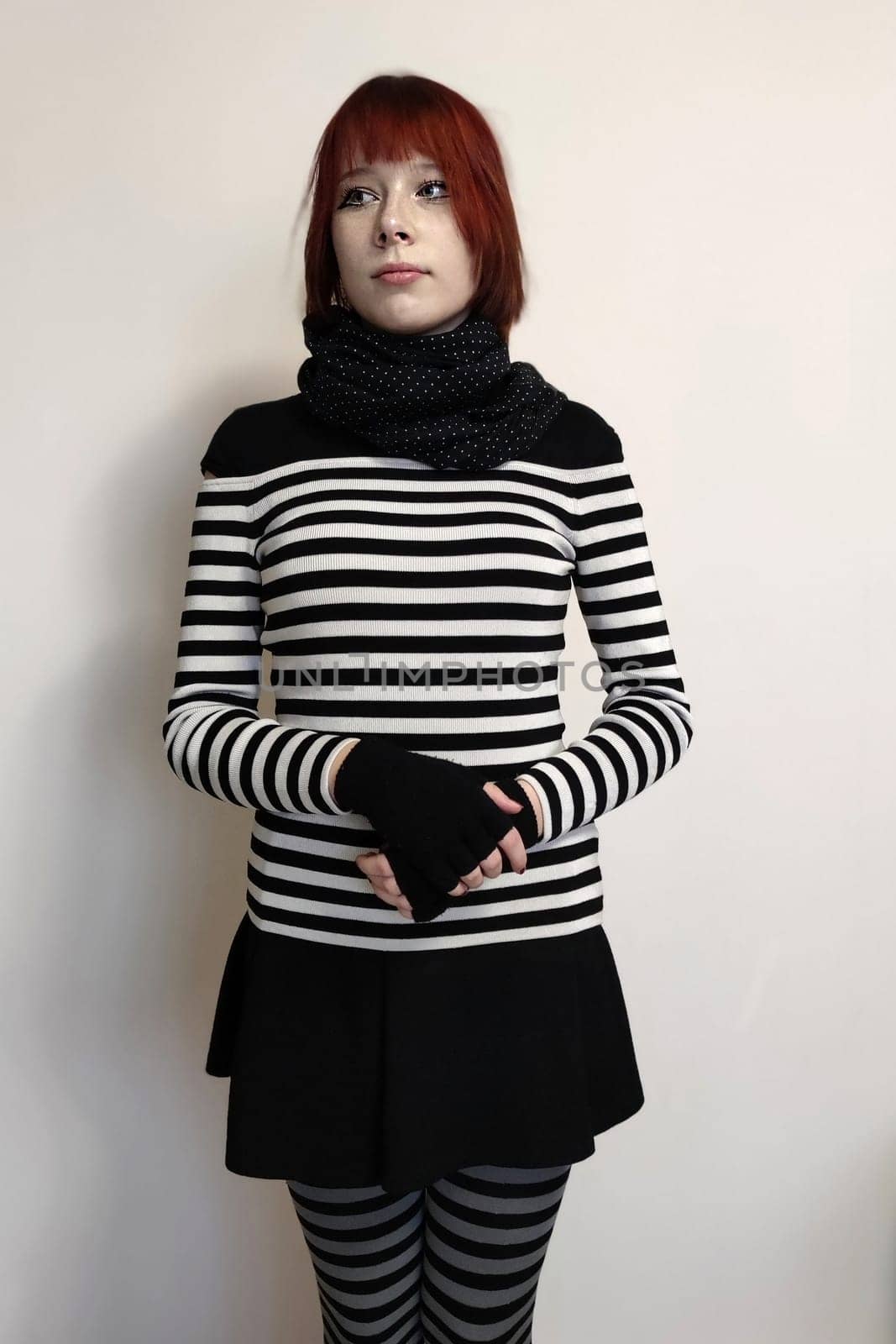 red-haired teen girl in striped clothes on a white background.