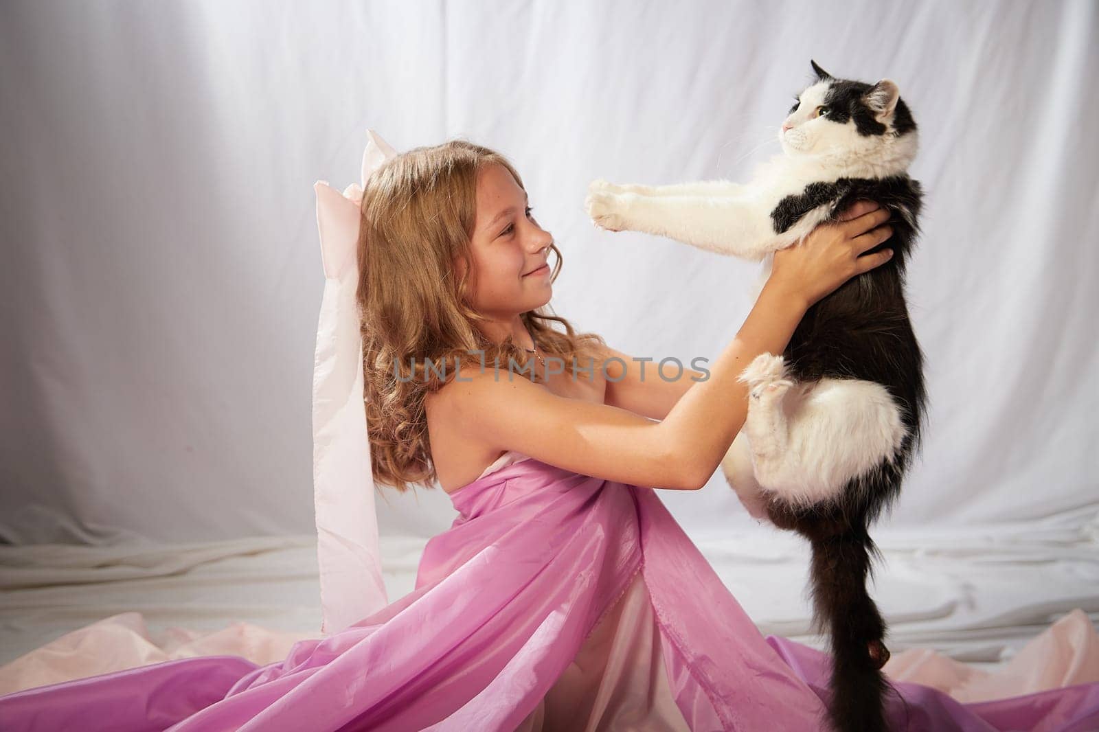 Portrait of cute kid girl posing in pink beautiful dress on white background. Model in studio looking as gentle magic princess from fairy taly having photo shoot on white background