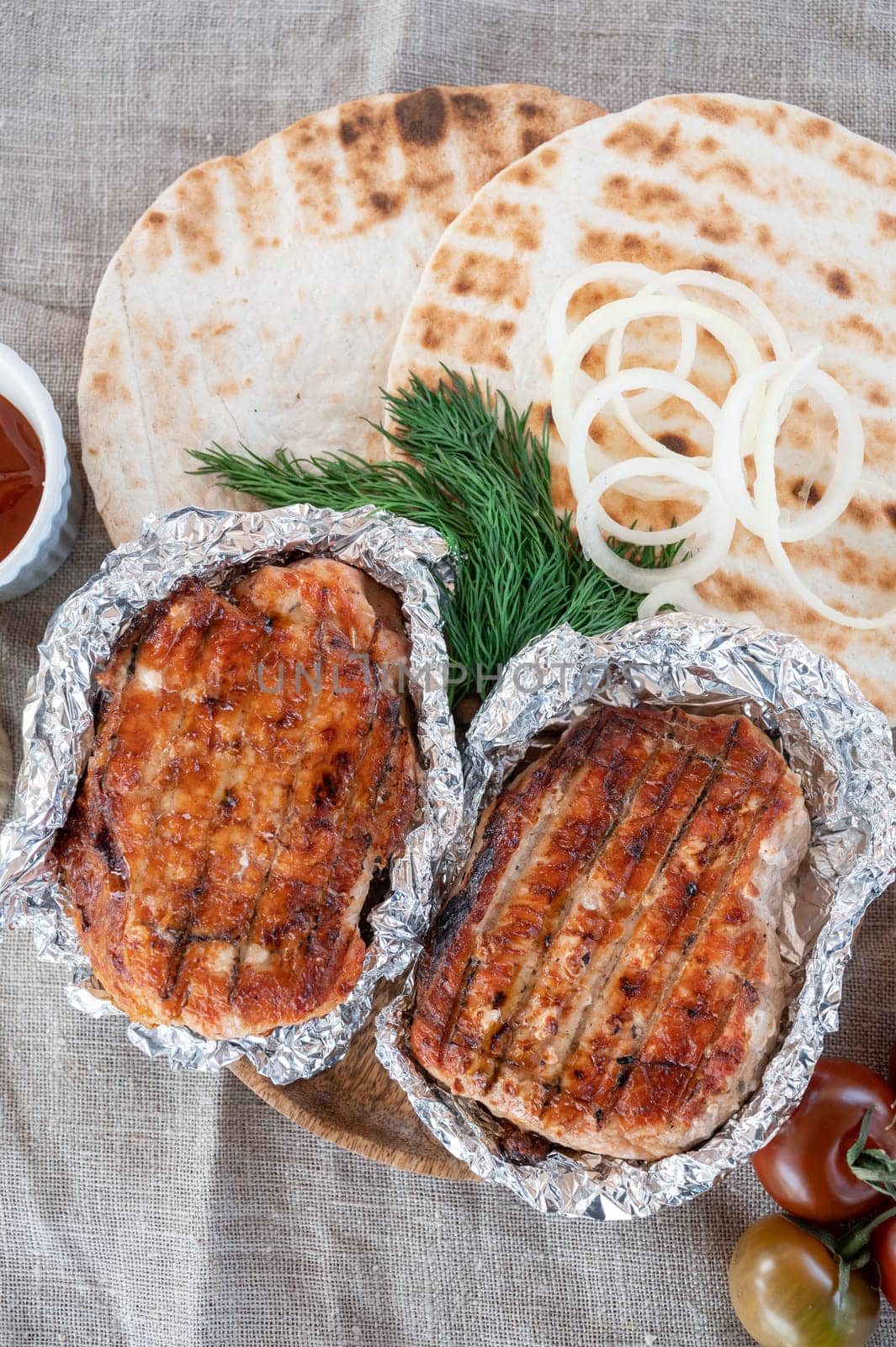 Grilled pork meat in foil with flapjack and vegetables. Summer rest concept