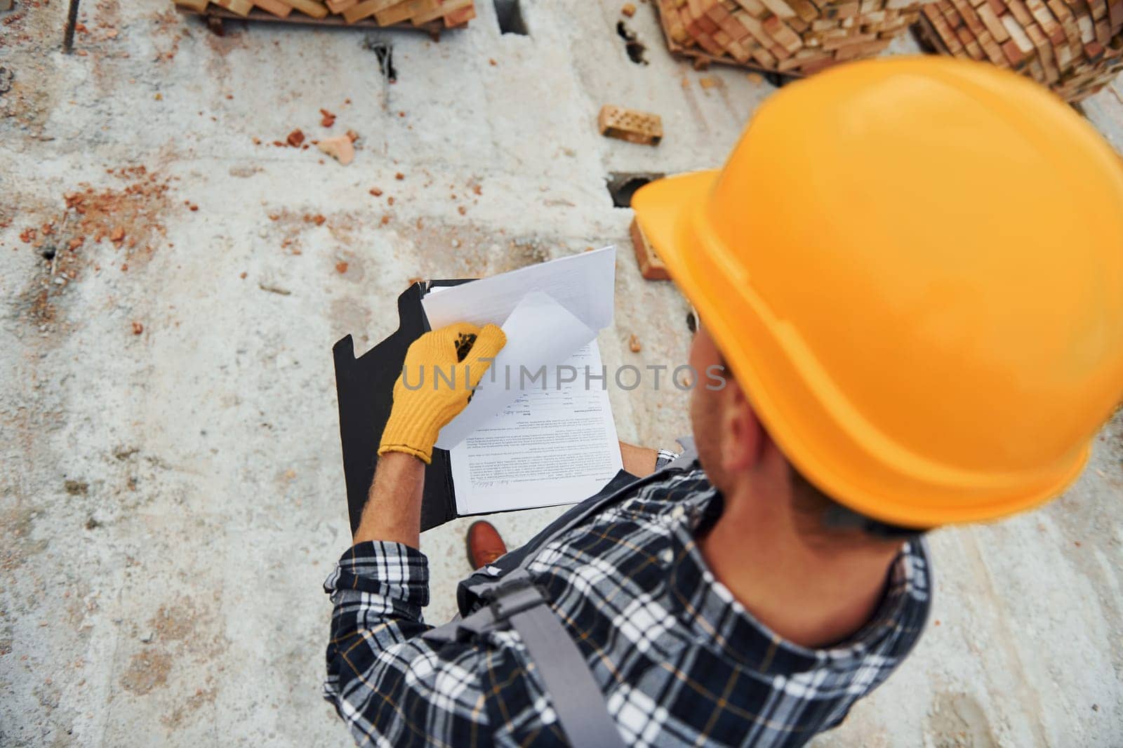 Top close up view of construction worker in uniform and safety equipment that have job on building.