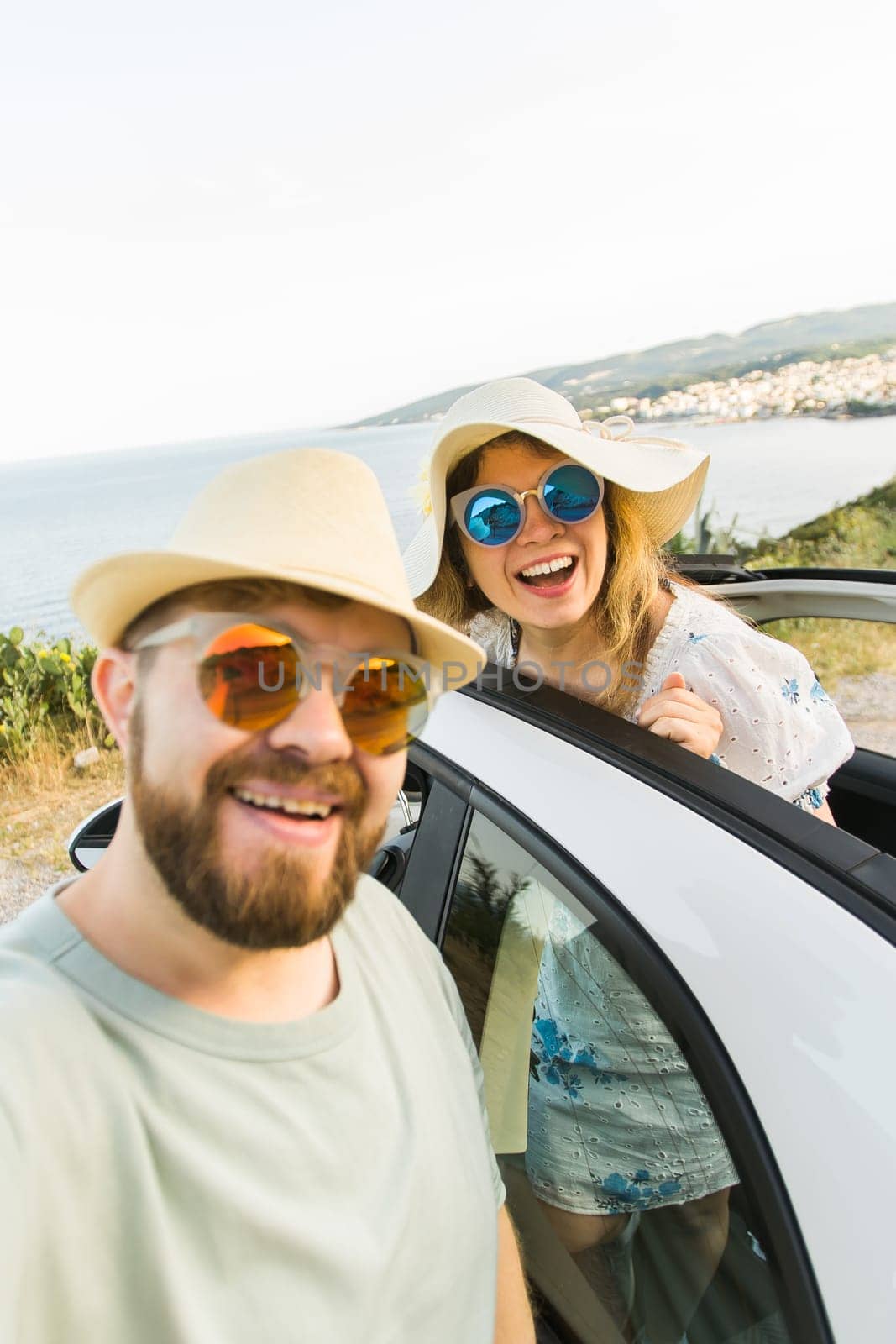 Happy beautiful couple in love taking a selfie portrait driving a convertible car on the road at vacation. Rental cars and vacation by Satura86