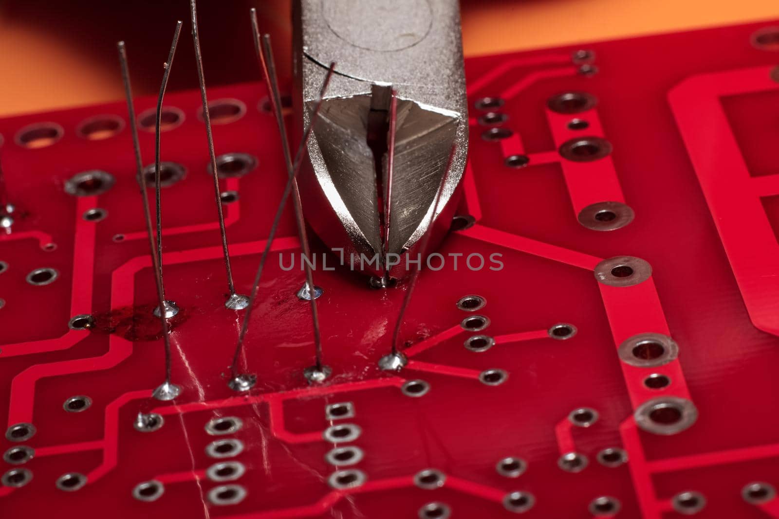 Red printed circuit board with wires and wire cutters close up