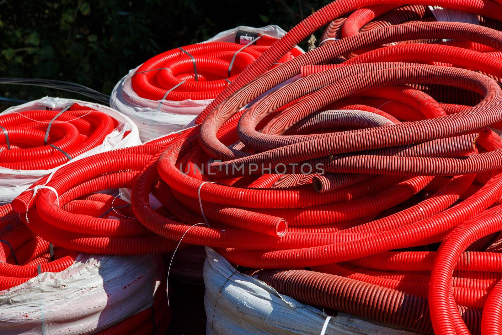 a pile of red corrugated PVC pipes for cable lay on the construction site, full frame background