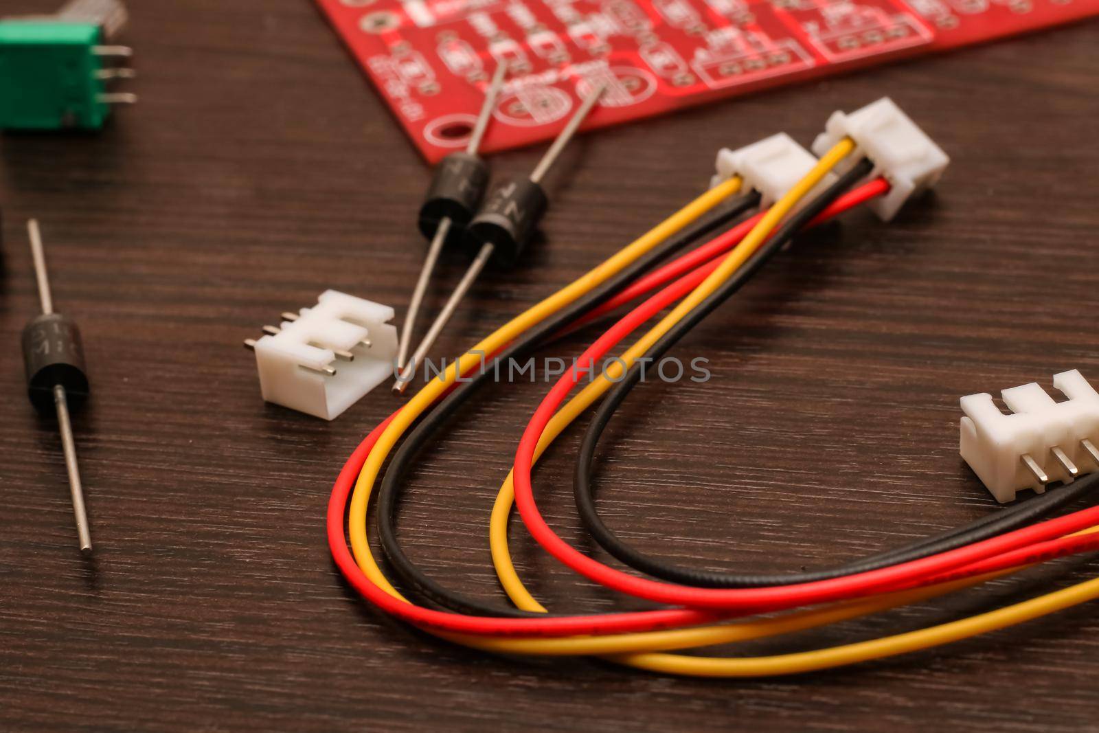 Colored wires, resistor and circuit board close-up on wooden table