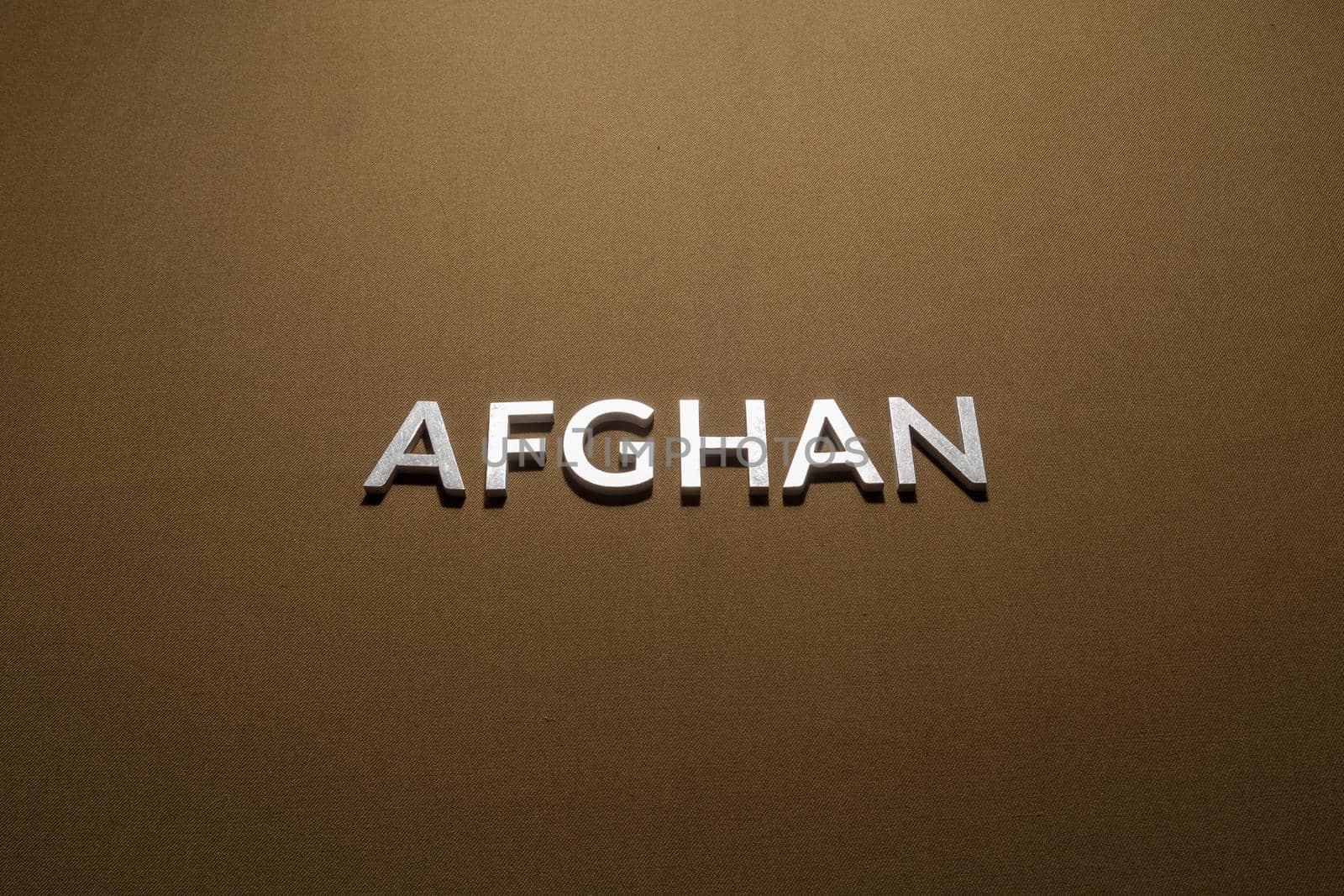 the word afghan laid with silver metal letters on tan khaki canvas fabric