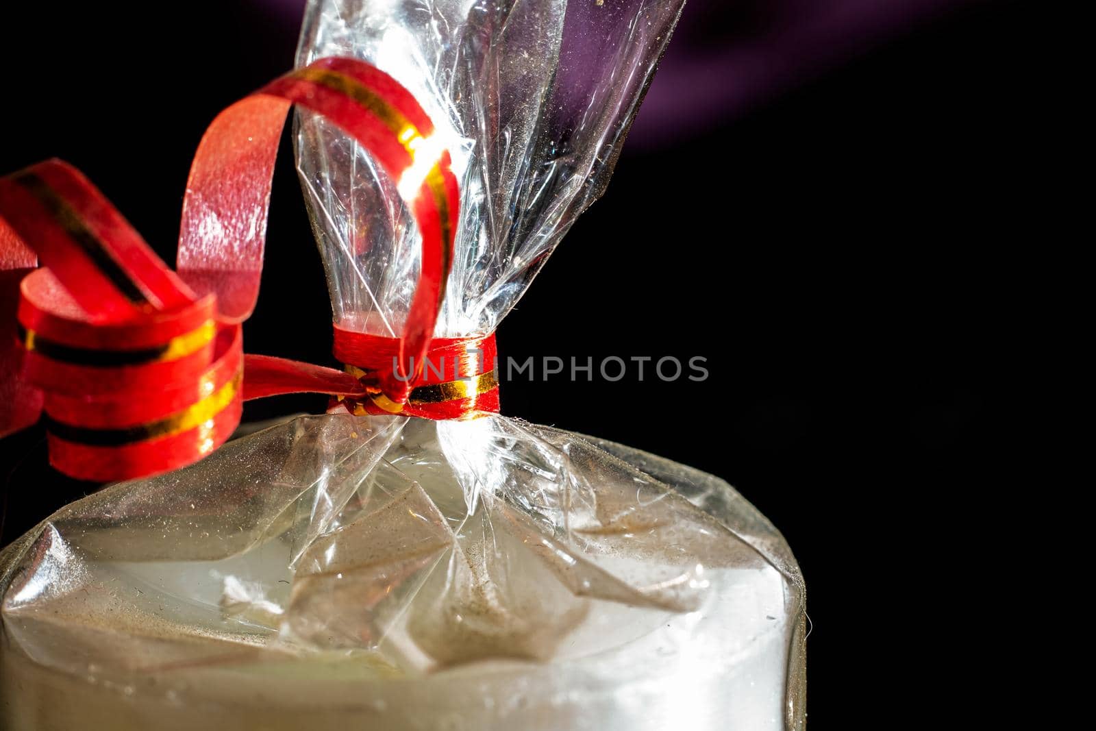 Gift wrap with red ribbon on black background close up