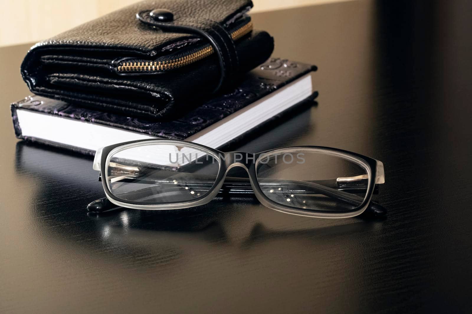 Glasses, wallet and notebook on a wooden table close up