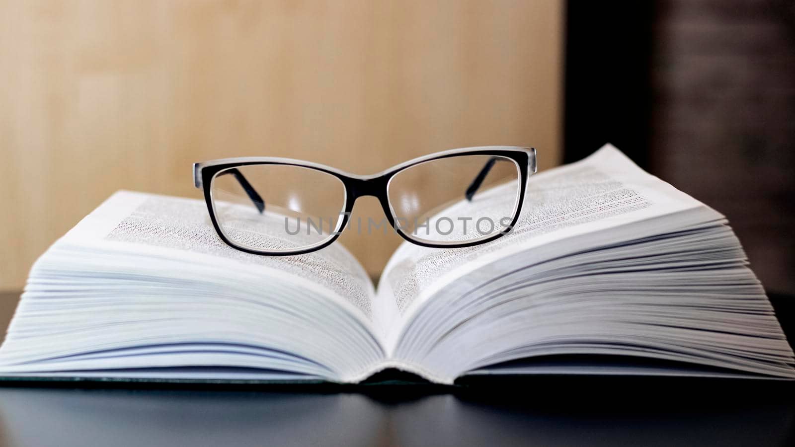 Glasses on an open book on a wooden table close up