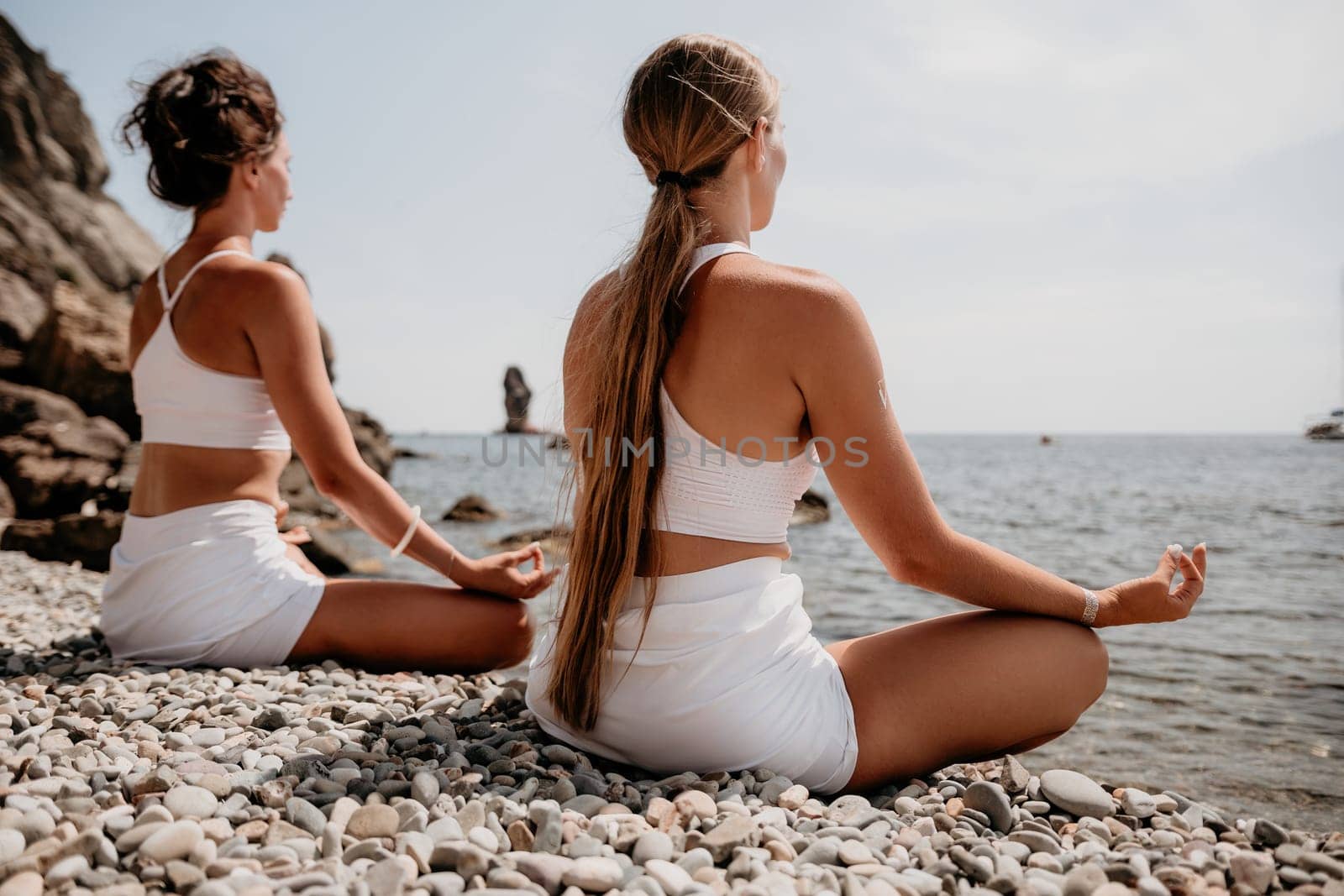 Woman sea yoga. Back view of free calm happy satisfied woman with long hair standing on top rock with yoga position against of sky by the sea. Healthy lifestyle outdoors in nature, fitness concept.