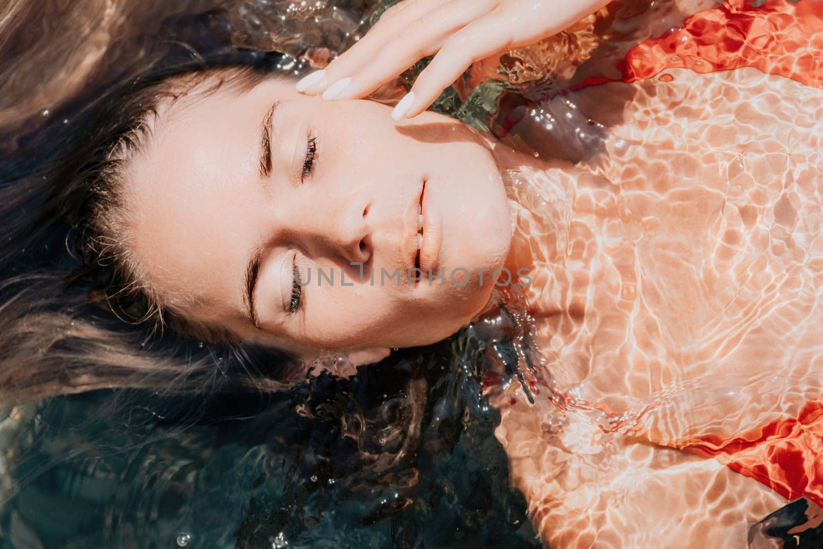 Side view a Young beautiful sensual woman in a mint long dress posing on a volcanic rock high above the sea during sunset. Girl on the nature on overcast sky background. Fashion photo