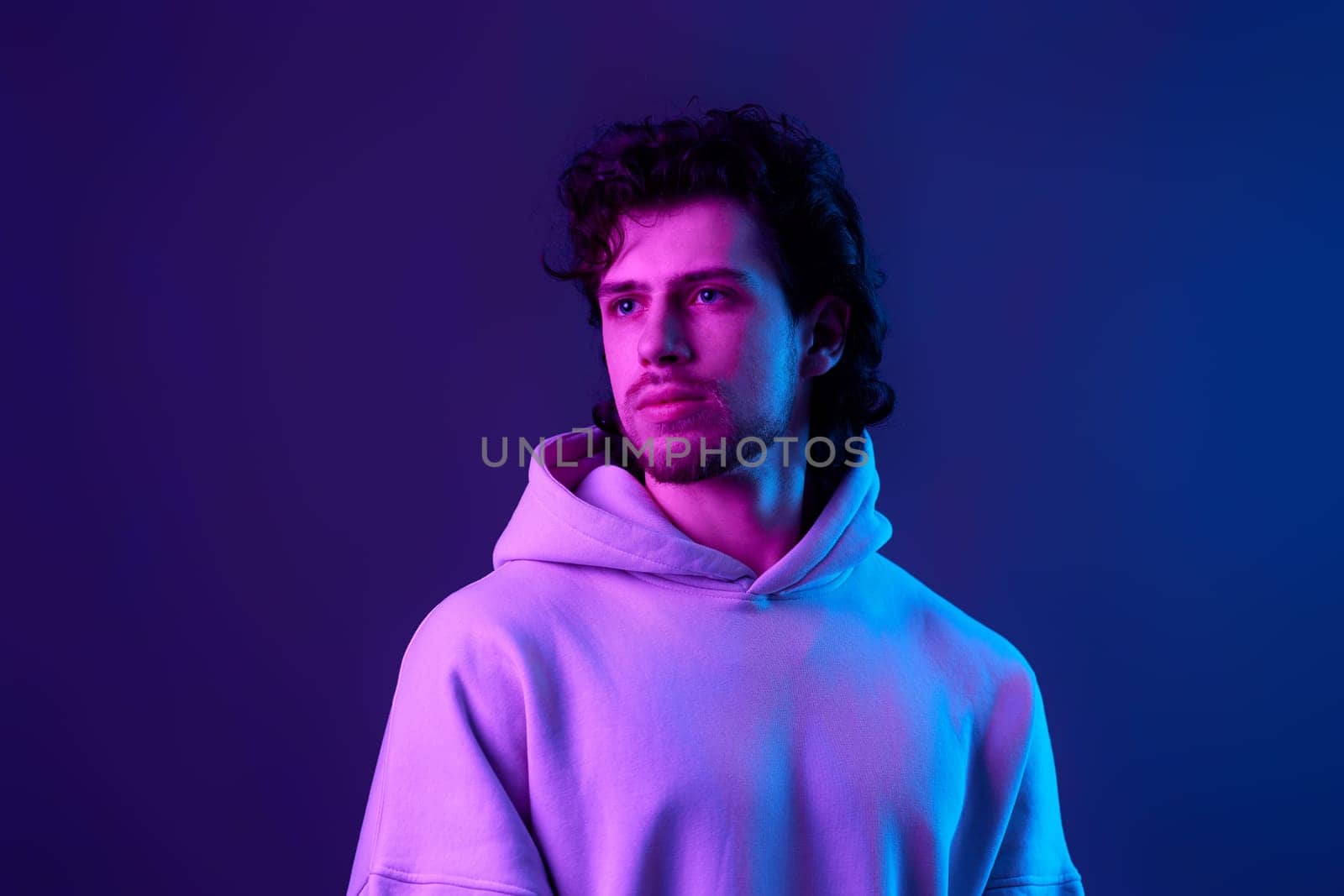 handsome bearded man in sweatshirt on blue background. Neon lighting
