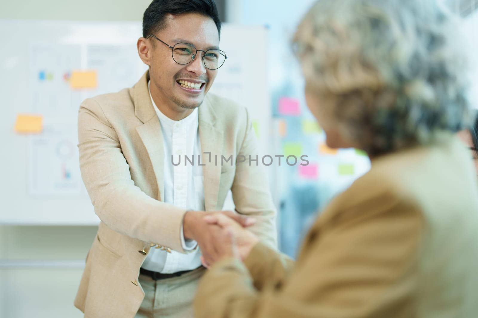 Asian entrepreneurs handshakes to congratulate the agreement between the two companies to enhance investment and financial strength. deal concept by Manastrong