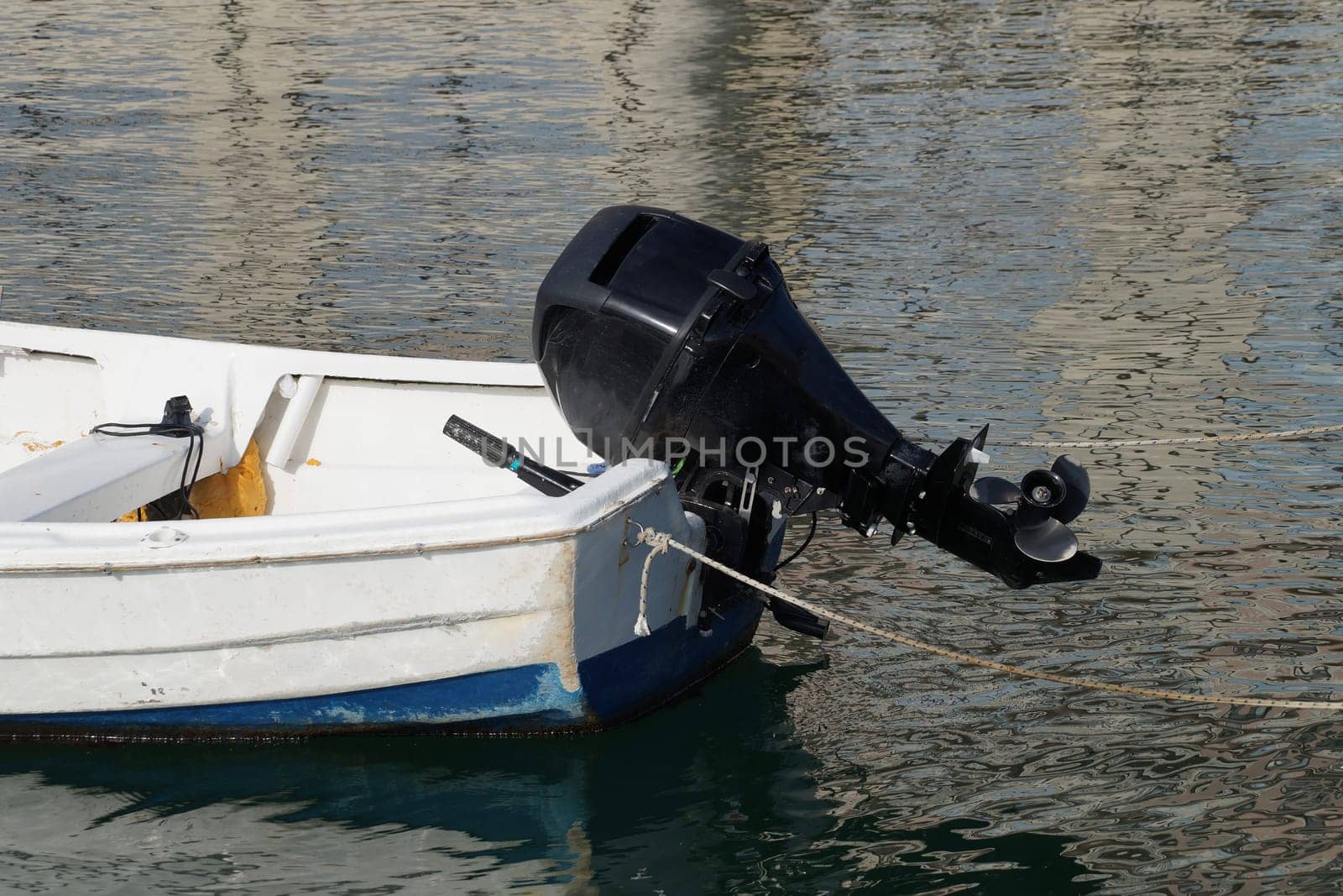 stern of a small boat with a motor on the water by Annado