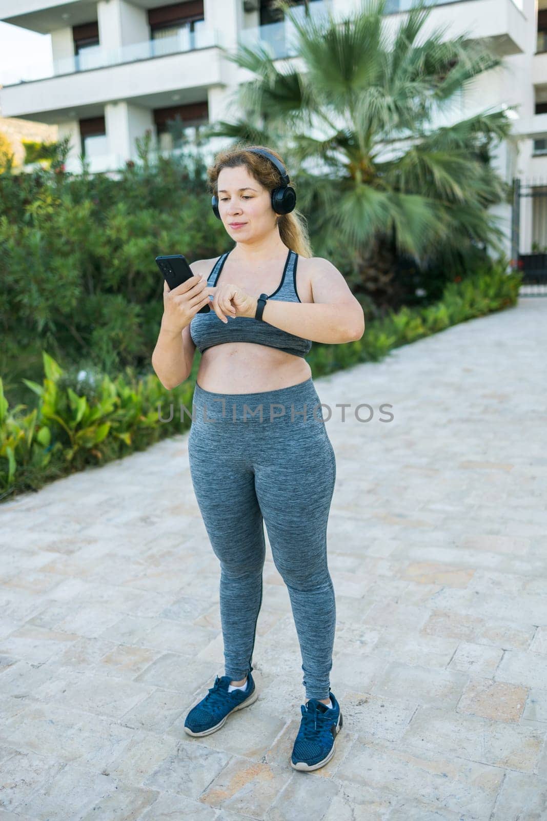 Fat woman checking time or heart rate from smart watch. Exercise or running outdoors for weight loss idea concept. Wellness and wellbeing by Satura86
