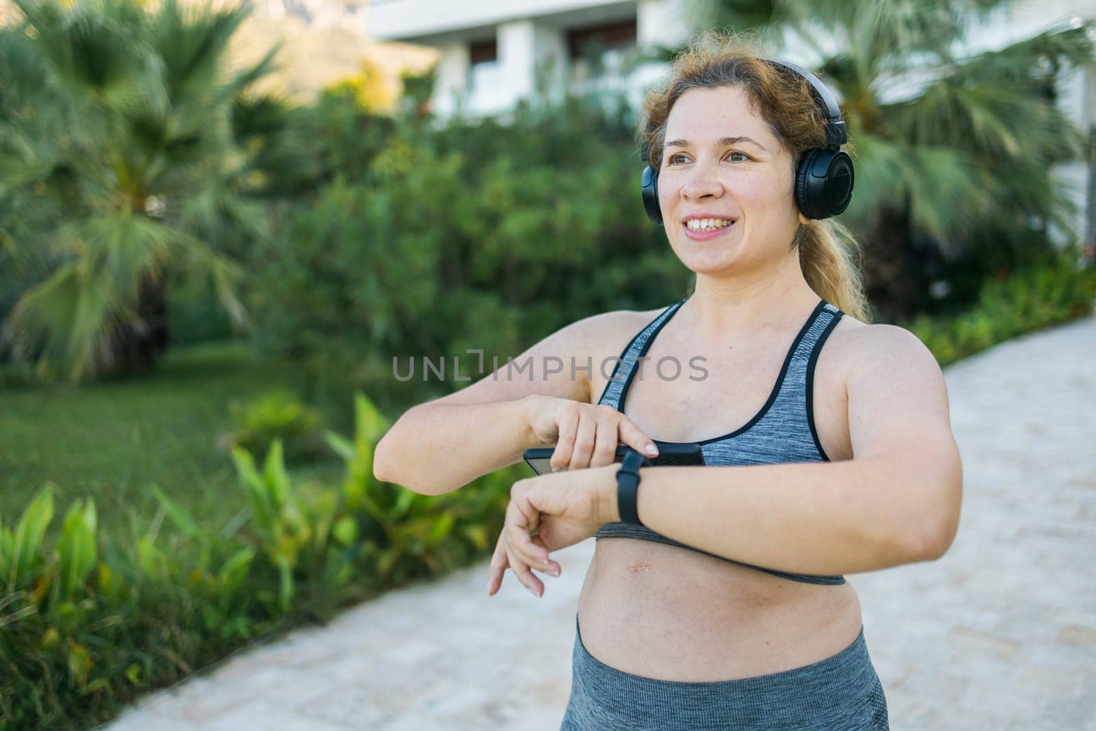 Fat woman checking time or heart rate from smart watch. Exercise or running outdoors for weight loss idea concept. Wellness and wellbeing copy space and empty space for text or advertising by Satura86