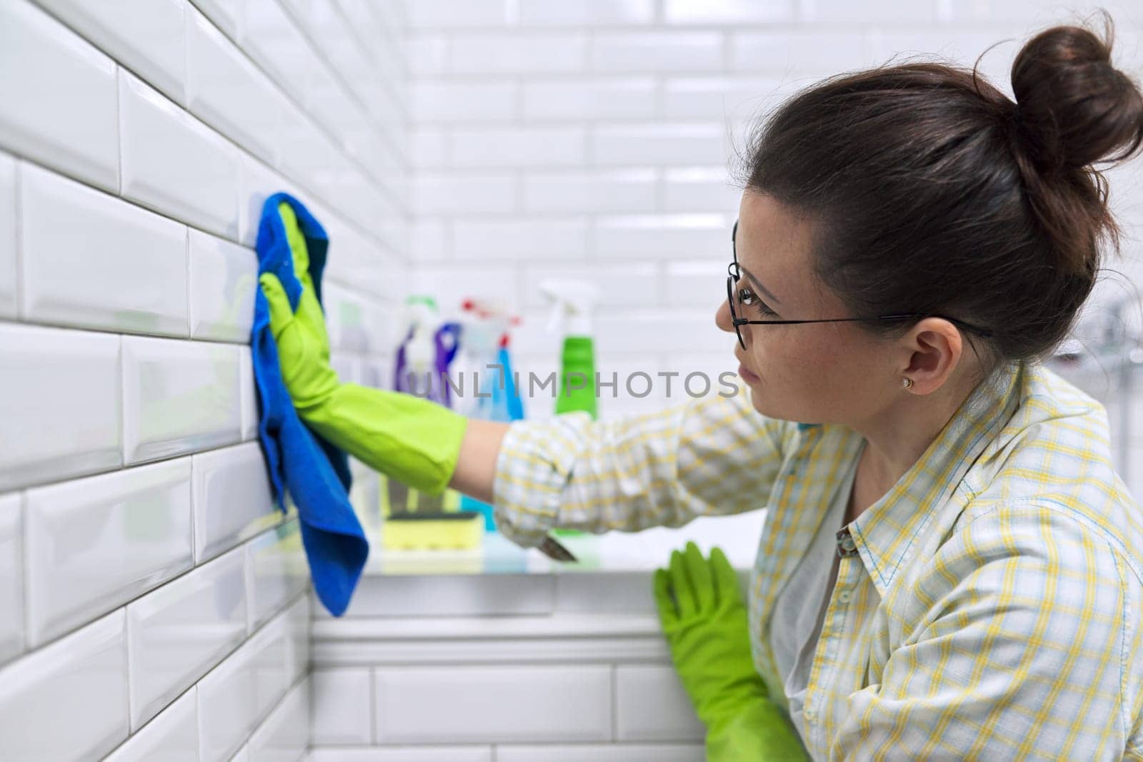 Female polishing tiled wall in bathroom with microfiber cloth by VH-studio