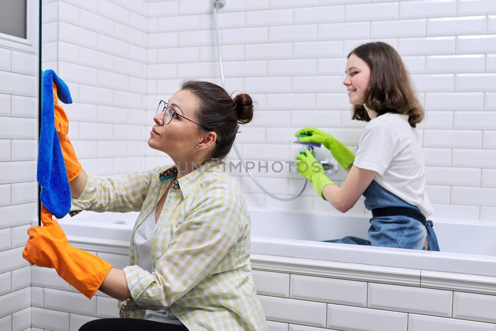 Family mother and teenage daughter cleaning together at home in the bathroom. Child helping parent, housekeeping, lifestyle, housework