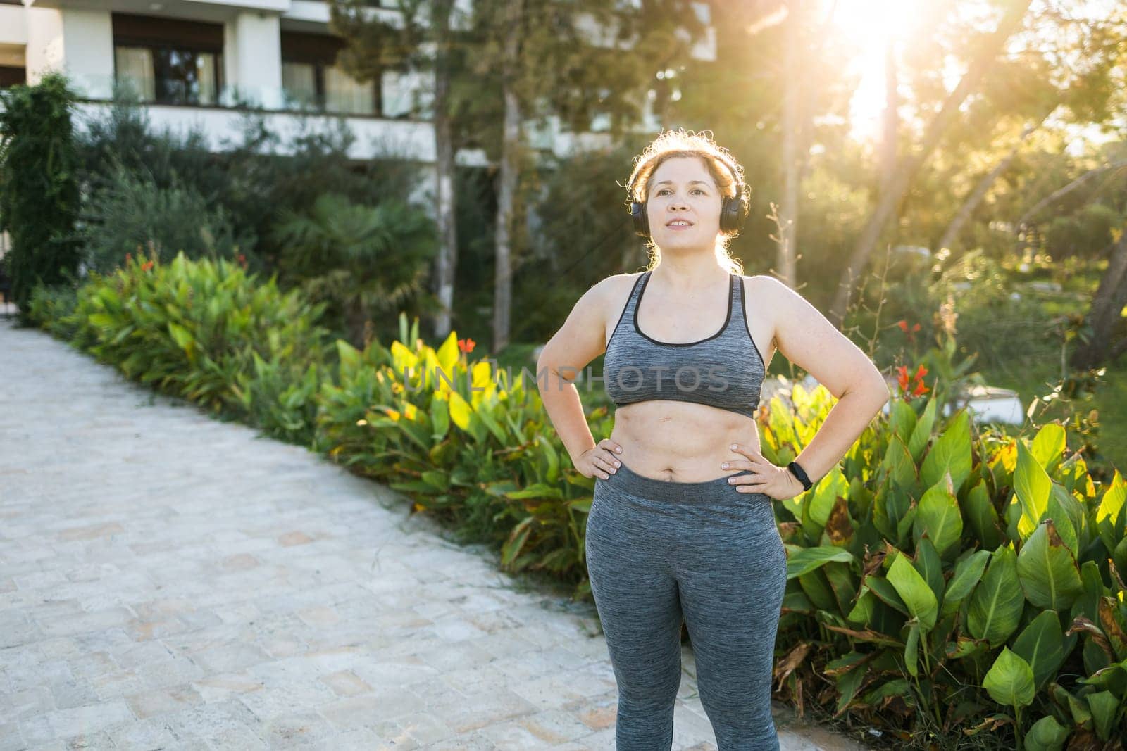 Fat woman and sports. Girl doing exercise for weight loss in the fresh air and smiling after training. Copy space and empty place for text or advertising by Satura86