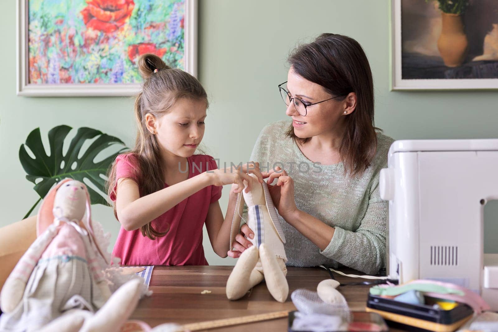Happy mother and daughter sewing together toy bunny doll at home. Family, hobbies and leisure, creativity, lifestyle, skills and learning, parent child communication, mothers day