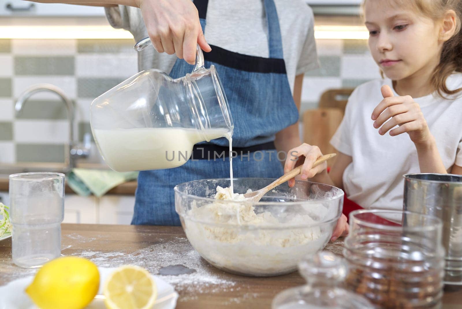 Children mix the flour in bowl, pour milk in dough by VH-studio