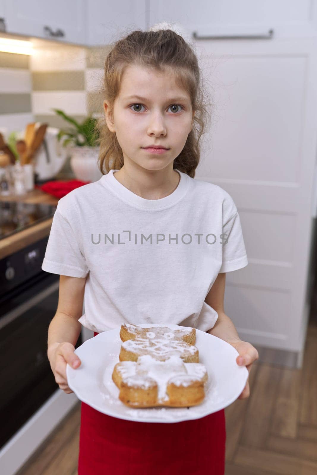 Girl child with freshly baked muffin in cat form sprinkled with icing sugar by VH-studio