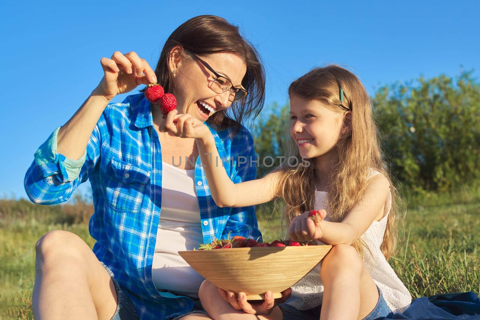 Happy laughing mother and child daughter together, picnic with bowl of fresh strawberries by VH-studio
