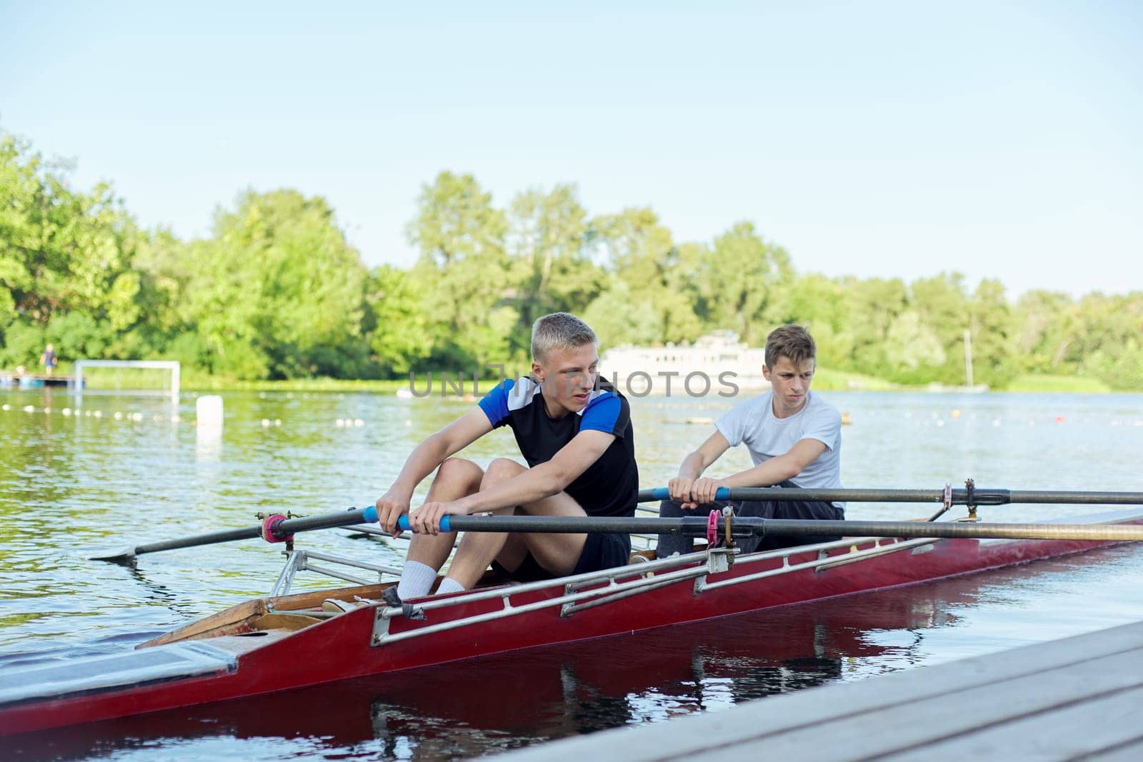 Team of two teenage boys kayaking on river by VH-studio