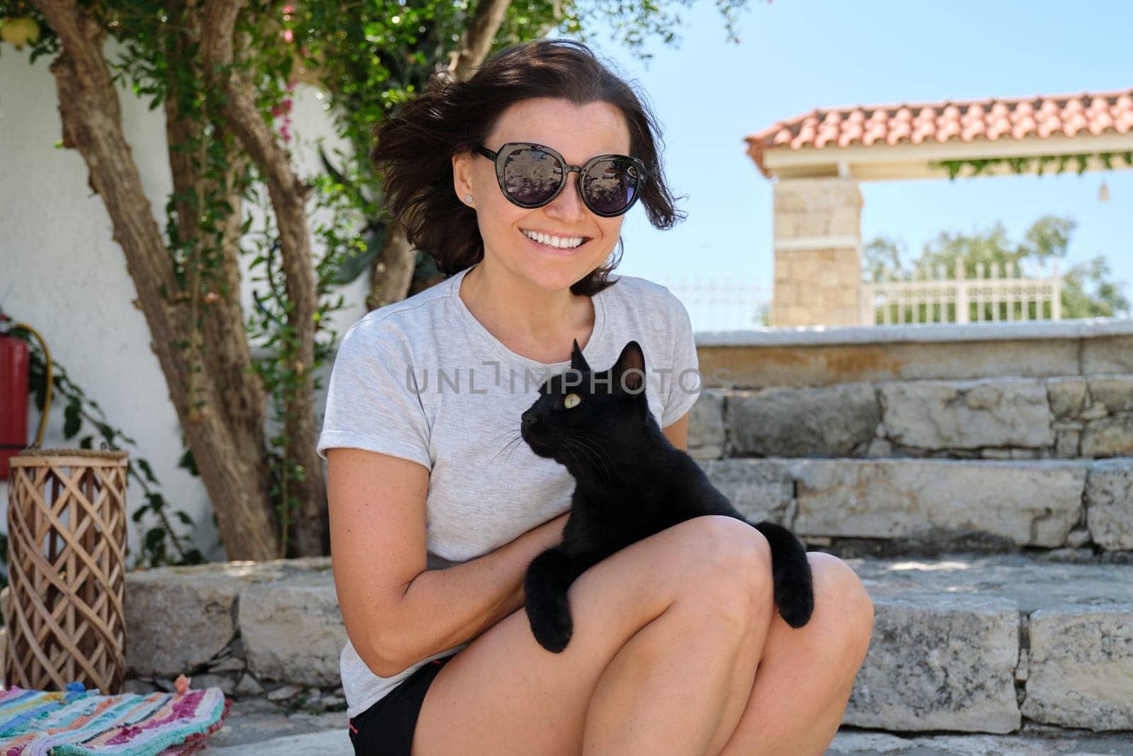 Happy woman with black cat, outdoor portrait of owner and pet.