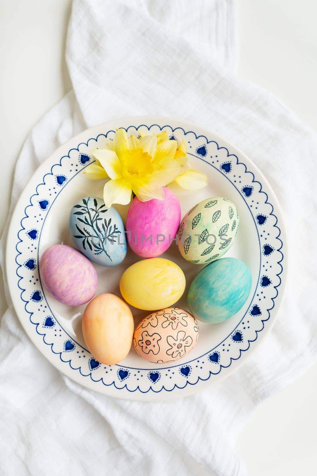 Easter eggs are painted in different colors and patterns on the plate. Top view, Easter celebration concept