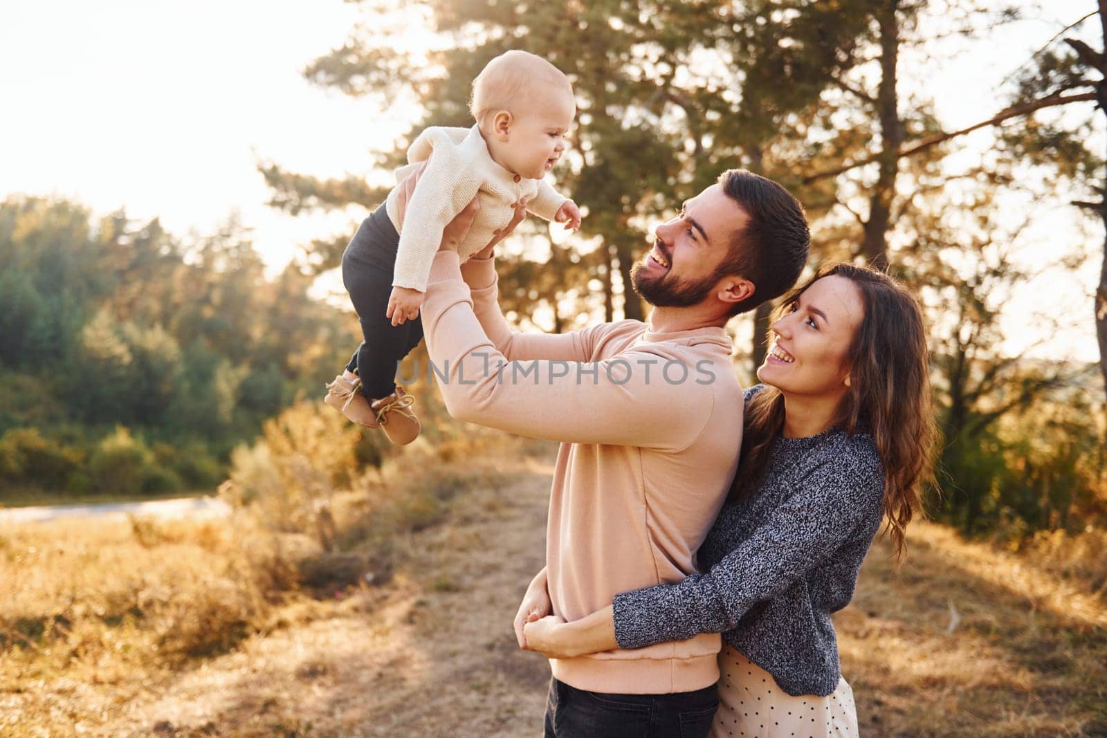 Happy family of mother, family and little baby rests outdoors. Beautiful sunny autumn nature.