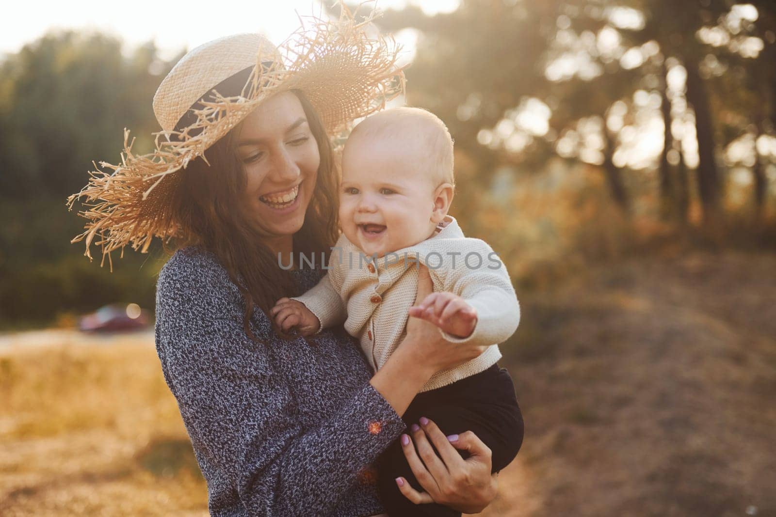 Young mother with her little baby rests outdoors at autumn season.