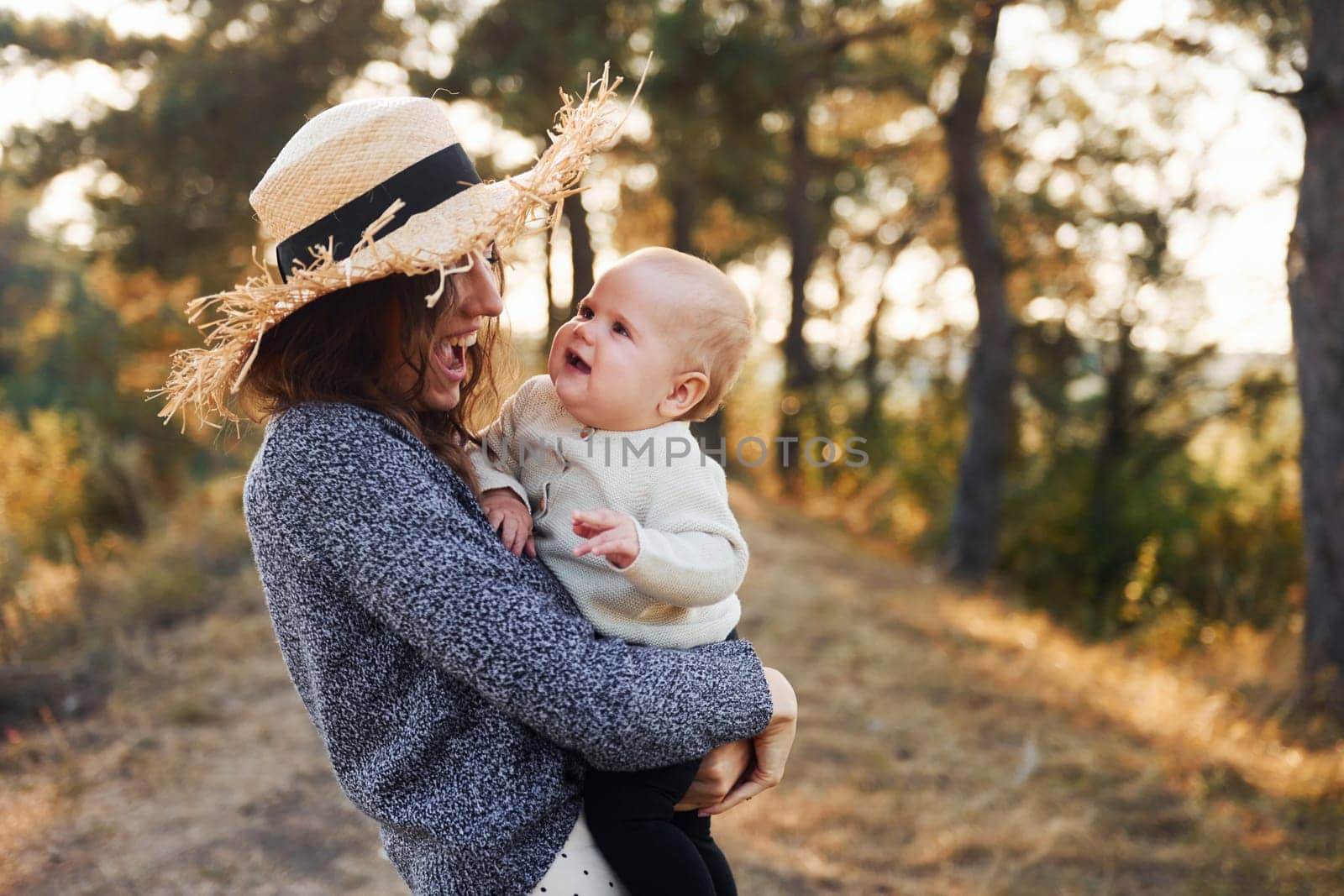 Playing together. Young mother with her little baby rests outdoors at autumn season.