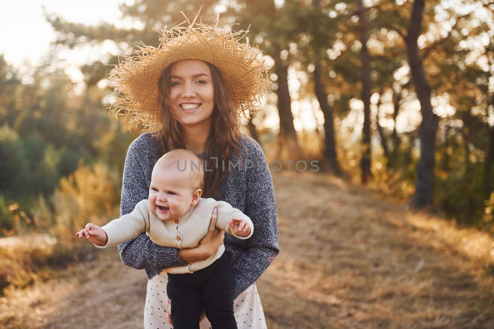 Playing together. Young mother with her little baby rests outdoors at autumn season.