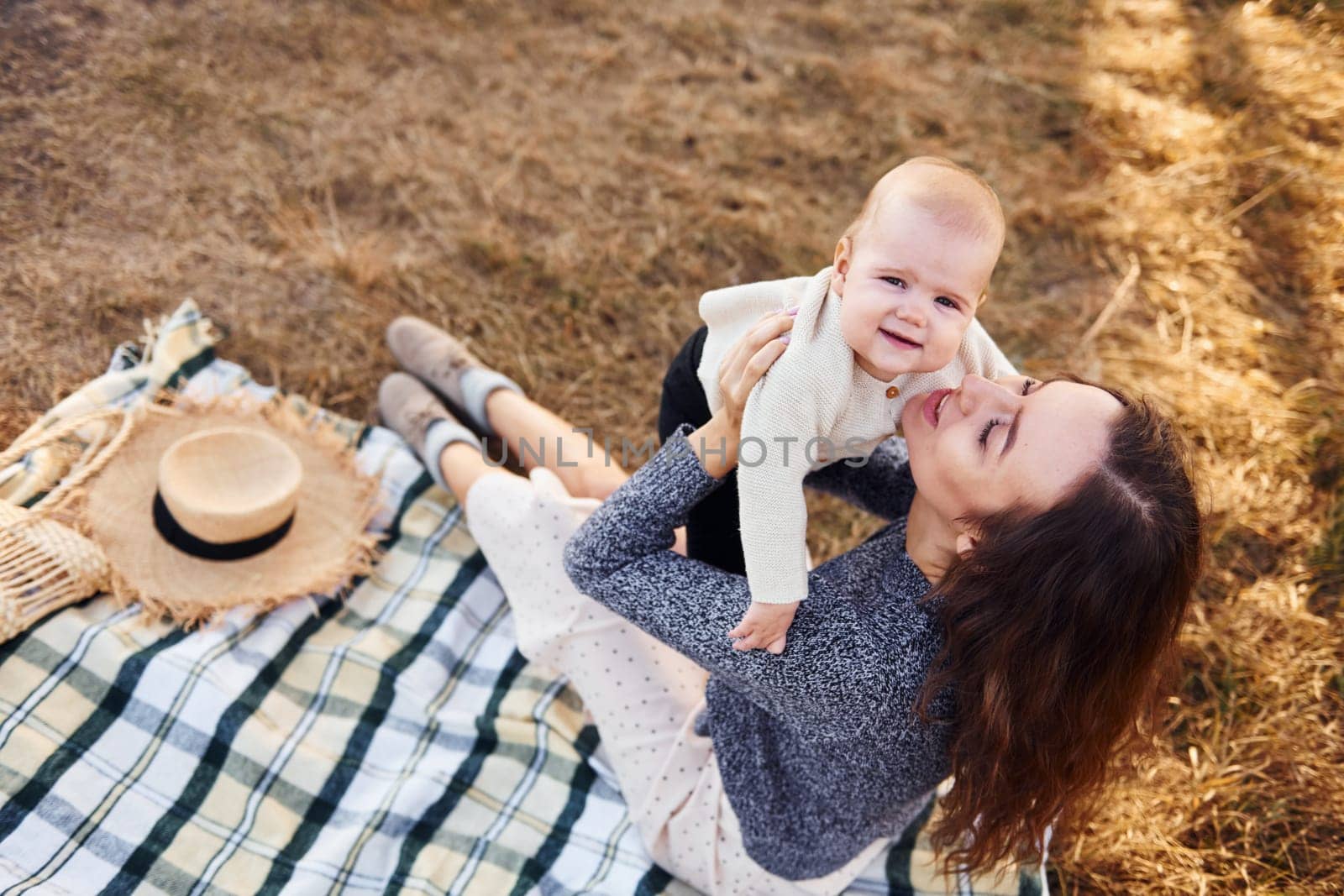 Young mother with her little baby rests outdoors at autumn season.